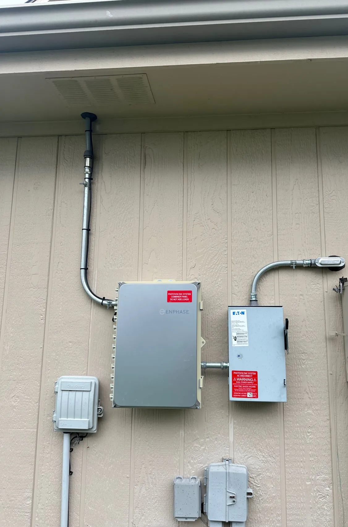 The solar wall on the audited Kansas City home: Enphase combiner, AC disconnect, conduit runs, and meter equipment mounted on tan siding